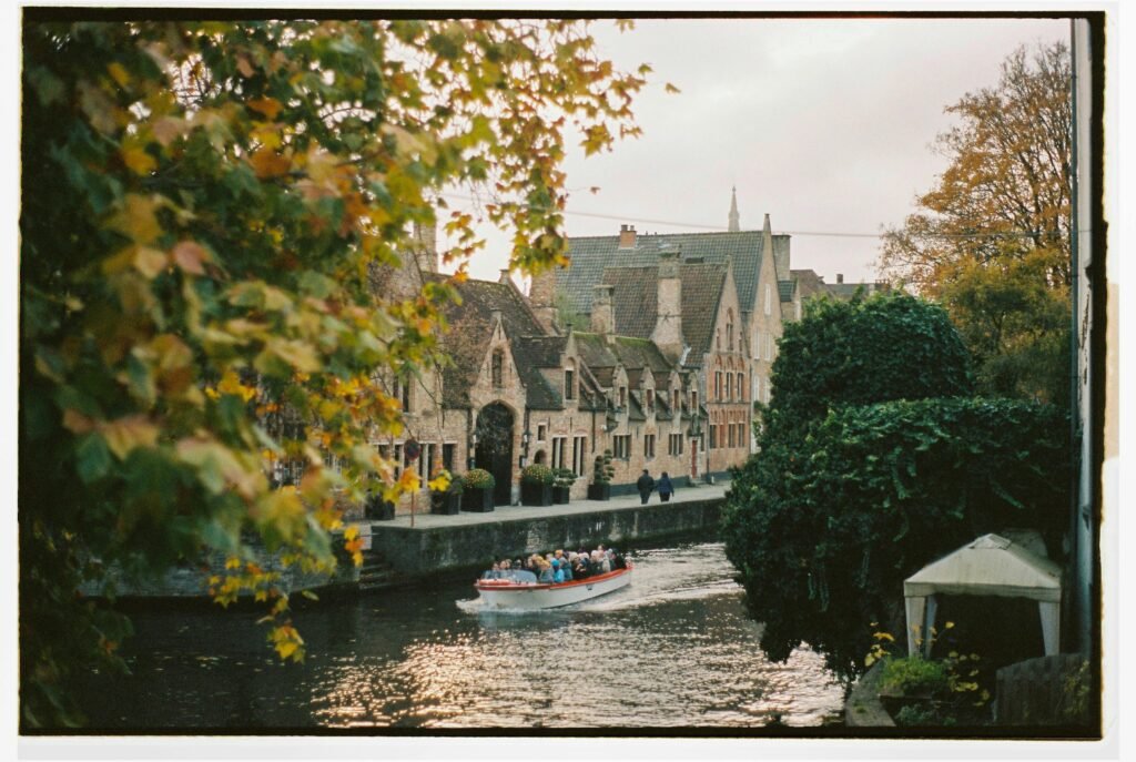 Charming autumn view of a boat tour on the scenic canals of Bruges, Belgium.